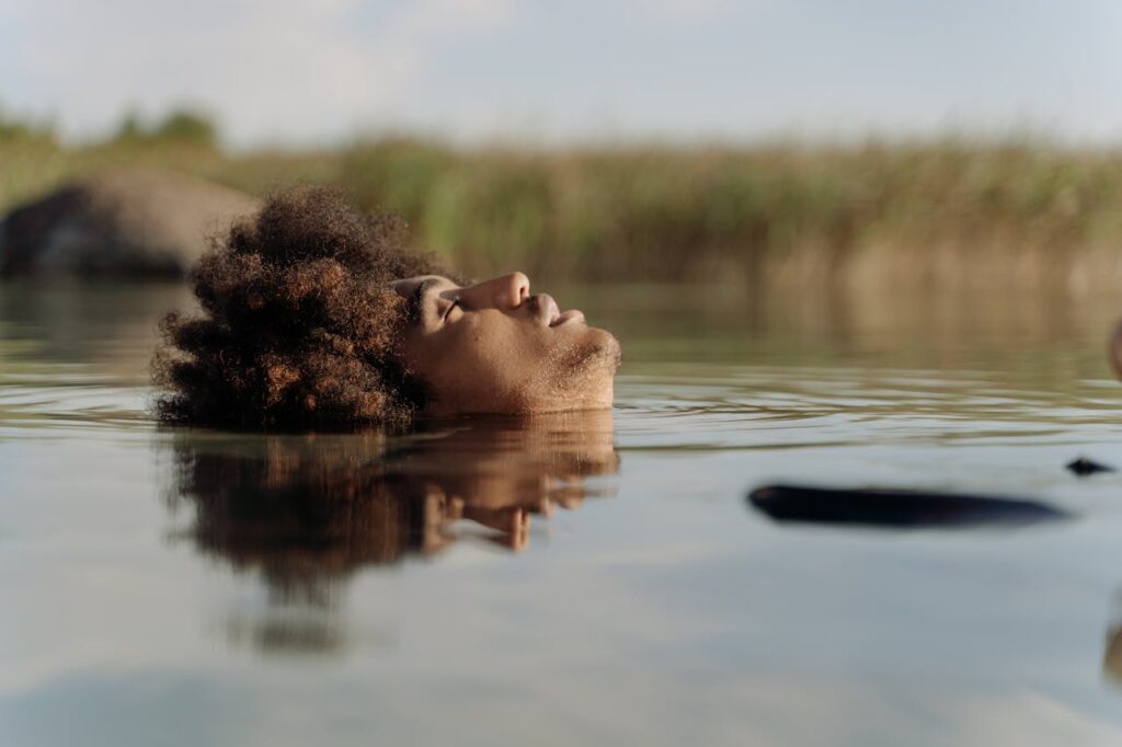 An adult relaxing in nature, floating peacefully on a calm body of water.
