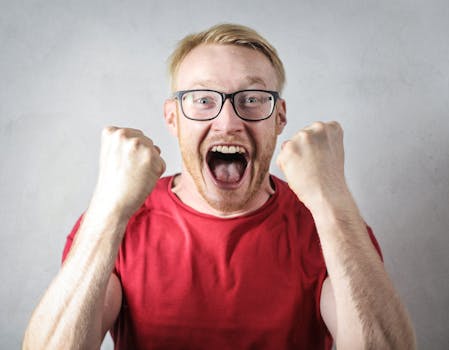 A cheerful man in a red shirt expressing excitement indoors.