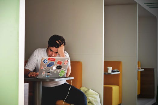 Man showing stress and frustration while working remotely on a laptop indoors.