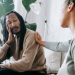 Two diverse individuals having an empathetic conversation in a cozy indoor setting.