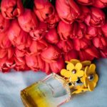 Elegant perfume bottle with red tulips on a soft background, radiating fragrance and beauty.
