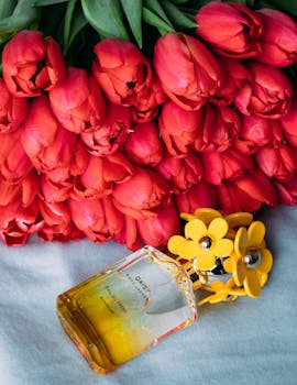 Elegant perfume bottle with red tulips on a soft background, radiating fragrance and beauty.